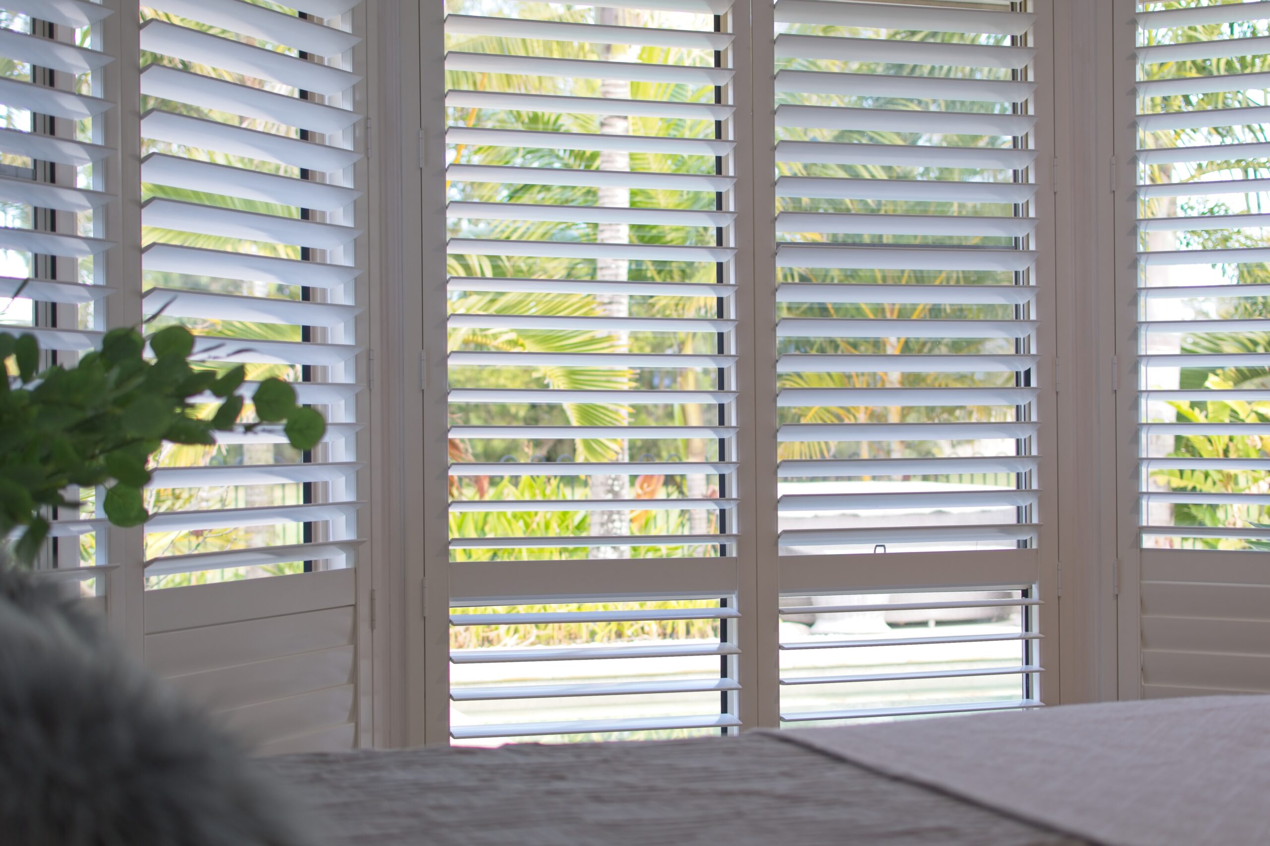 Luxury white indoor plantation shutters in a bedroom.